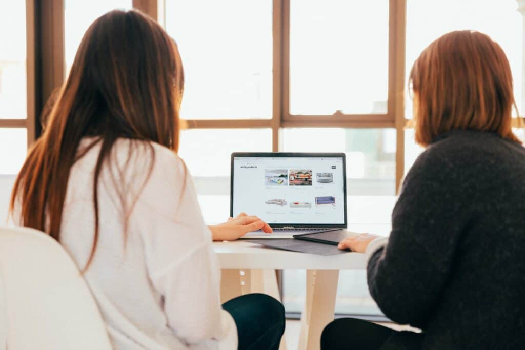 Two Women Looking At Website On Laptop