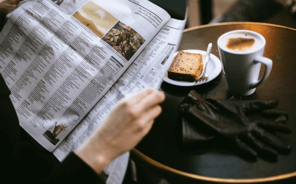 Person reading newspaper at a cafe