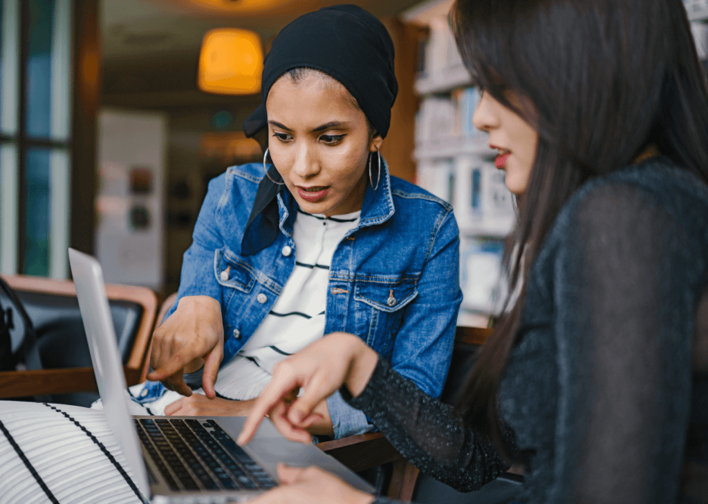 Two women looking at laptop screen and pointing