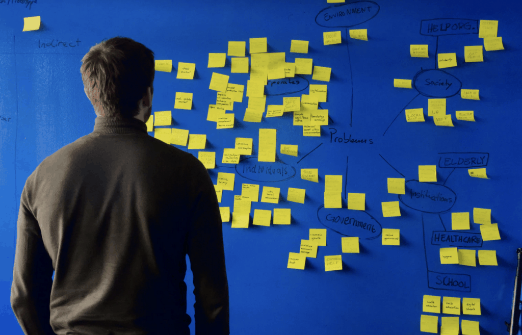 Man looking at wall with sticky notes on