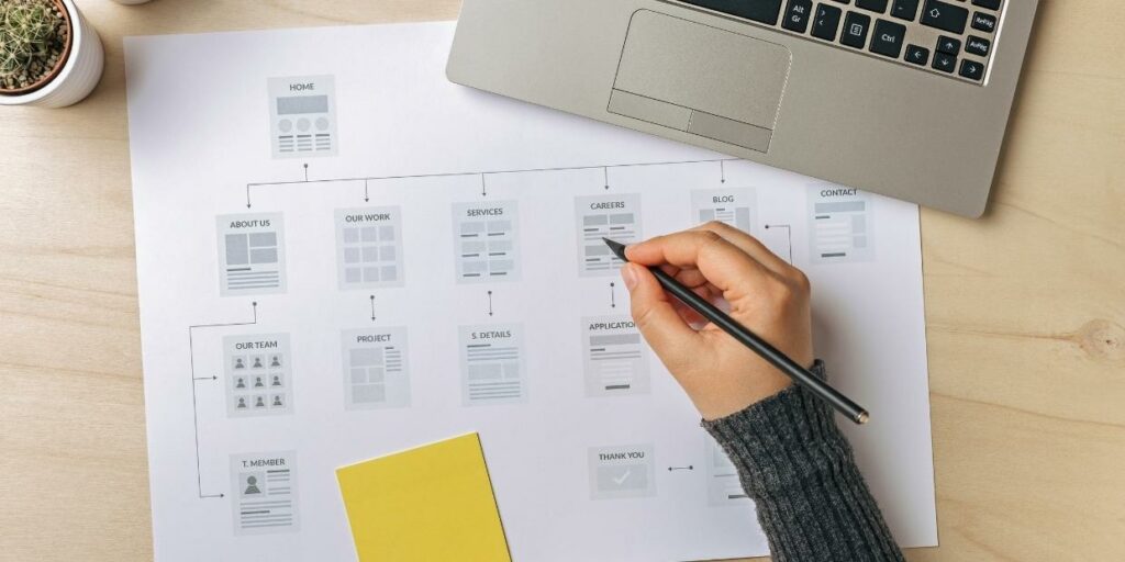 A person drawing on a sheet with a website site map printed on it