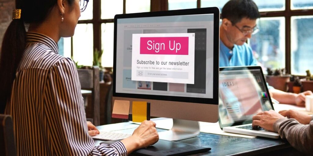 A woman using a desktop computer with a newsletter sign-up pop-up on the screen