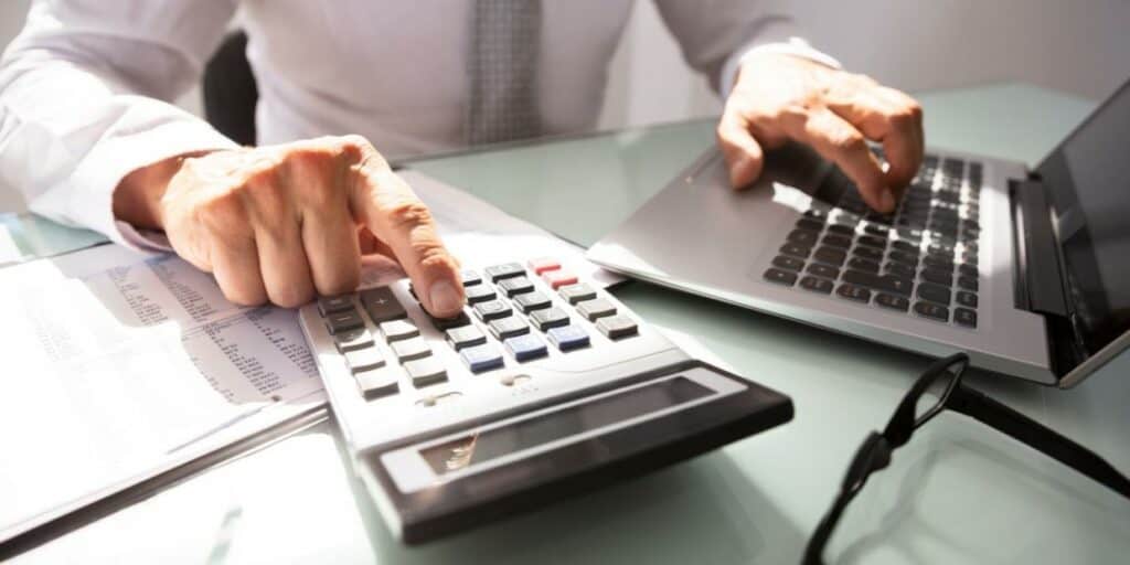 A businessman at a desk using a calculator budgeting for building and construction trade shows